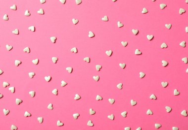 Pembe arka planda beyaz kalp şekilli serpintiler, düz uzanmış