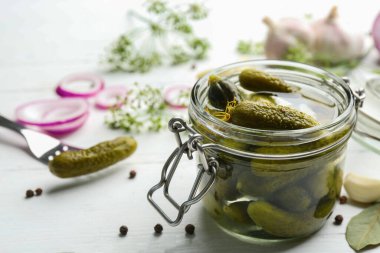 Beyaz ahşap masada cam kavanoz salatalık turşusu. Metin için boşluk