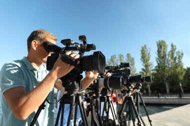 Güneşli bir günde dışarıda çalışan profesyonel kameralı operatörler.