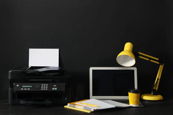 Modern printer, laptop and office supplies on black background