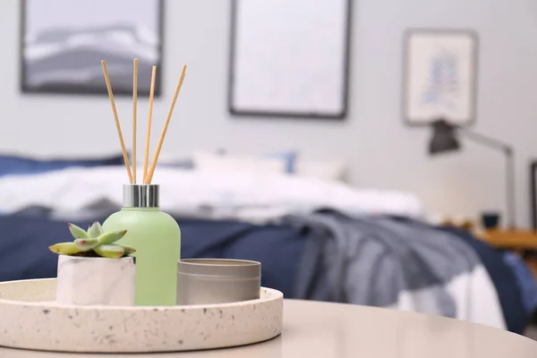 Aromatic reed air freshener, candle and houseplant on table in room. Space for text