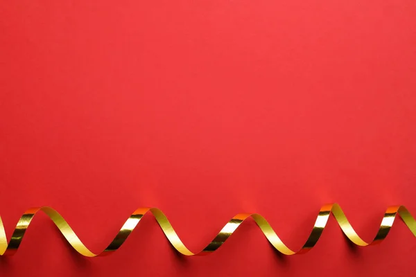 赤い背景に光沢のある黄金の蛇紋岩ストリーマー トップビュー テキストのスペース — ストック写真