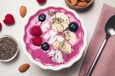 Gri masada servis edilen tatlı kasesinde meyve ve hindistan cevizi cipsi ile nefis acai smoothie.