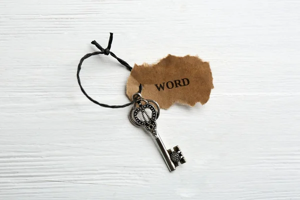 Key with tag WORD on white wooden background, top view. Keyword concept