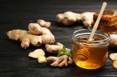 Siyah ahşap masada bal ve zencefil. Doğal soğuk algınlığı ilaçları.