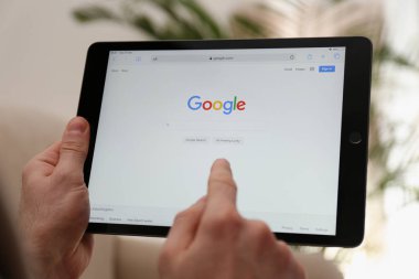 MYKOLAIV, UKRAINE - 27 Ekim 2020: Tablet üzerinde Google arama motoru kullanan adam bulanık arkaplan, yakın plan