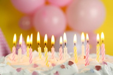 Bulanık arkaplanda yanan mumlarla doğum günü pastası, yakın plan.