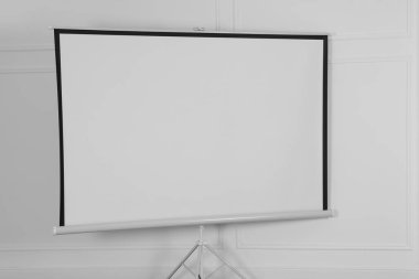 Beyaz duvarın yanındaki boş projeksiyon ekranı. Tasarım için boşluk