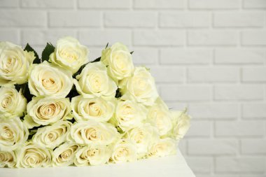 Beyaz tuğla duvarın yanında taze gül buketi, yakın plan.