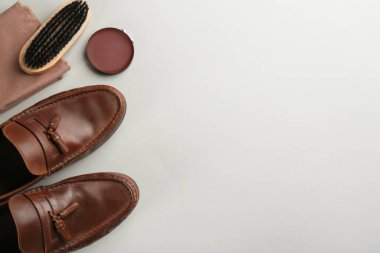 Açık gri arka planda ayakkabı bakım aksesuarları ve ayakkabıları olan düz bir kompozisyon. Metin için boşluk