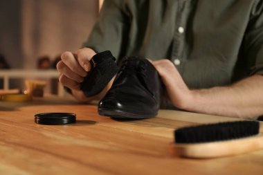 Atölyede profesyonel olarak siyah deri ayakkabıyla ilgilenen adam.