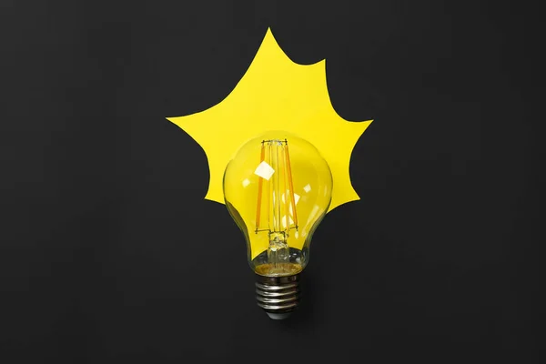 黒の背景に光を模倣黄色の紙とランプ電球 フラットレイアウト — ストック写真