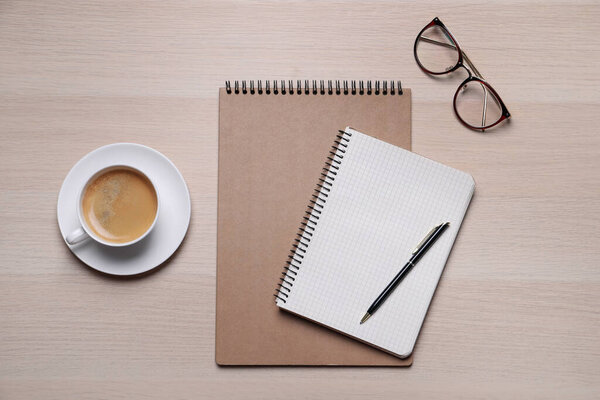 Notebooks, coffee and glasses on wooden table, flat lay
