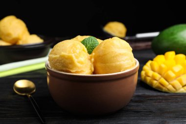 Siyah ahşap masada kasede nefis mango dondurması.