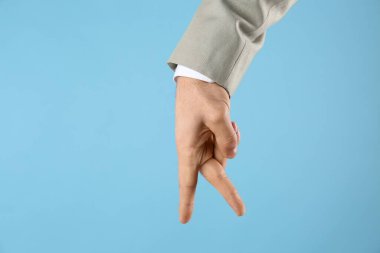 İş adamı elini açık mavi arka planda gezdirir, yakın plan. Parmak hareketi.