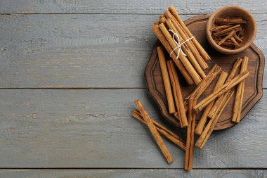 Aromatik tarçın çubukları gri ahşap masada, düz yerde. Metin için boşluk