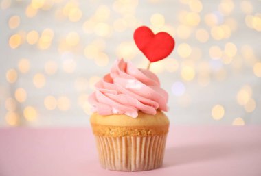 Sevgililer Günü için pembe masada bulanık ışıklara karşı lezzetli bir kek.