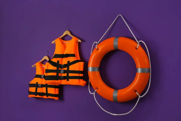 紫色の背景にオレンジのライフジャケットとライフブイ 救助装置 — ストック写真