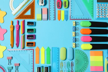 Açık mavi arkaplandaki farklı kırtasiye malzemelerinin çerçevesi düz. Okula geri dön.