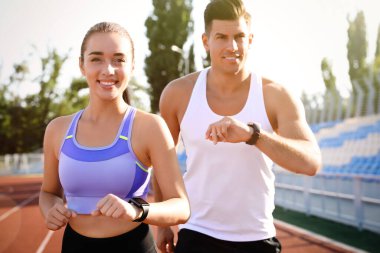 Stadyumda spor takip cihazları olan bir çift koşuyor.