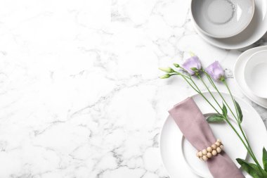 Düz kompozisyon, güzel bulaşık takımları ve beyaz mermer masa üzerinde çiçekler. Metin için boşluk