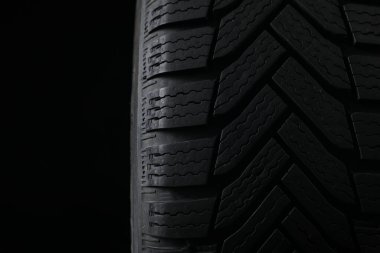 Siyah arka planda kış lastiği, yakın plan. Araba bakımı
