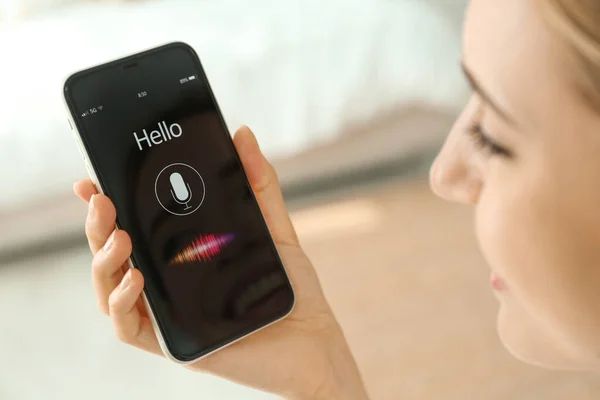 Young woman using voice search on smartphone indoors, closeup