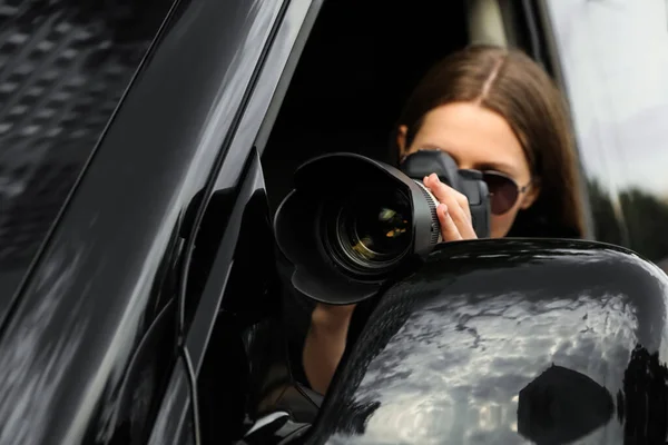 Private detective with camera spying from car, focus on lens