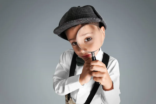 Liten Pojke Med Förstoringsglas Leka Detektiv Grå Bakgrund — Stockfoto