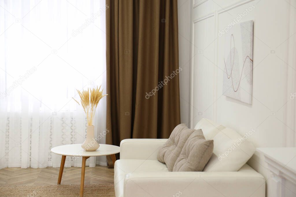 Sofa and window with brown curtains in simple room interior