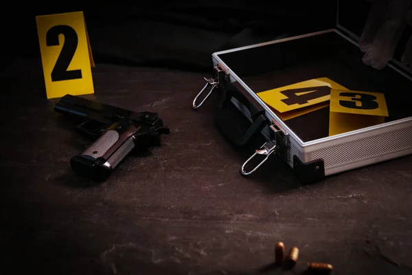 ブラックスレートテーブルの証拠マーカーで銃とオープンケース 犯罪現場 — ストック写真