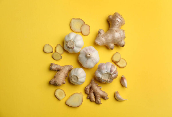 Ginger and garlic on yellow table, flat lay. Natural cold remedies