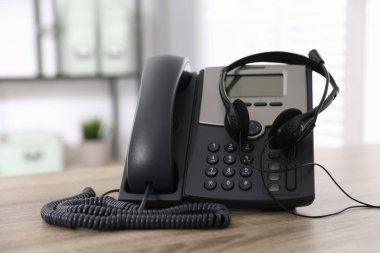 Masaüstü telefonu ve kulaklığı ofisteki ahşap masada. Yardım hattı servisi