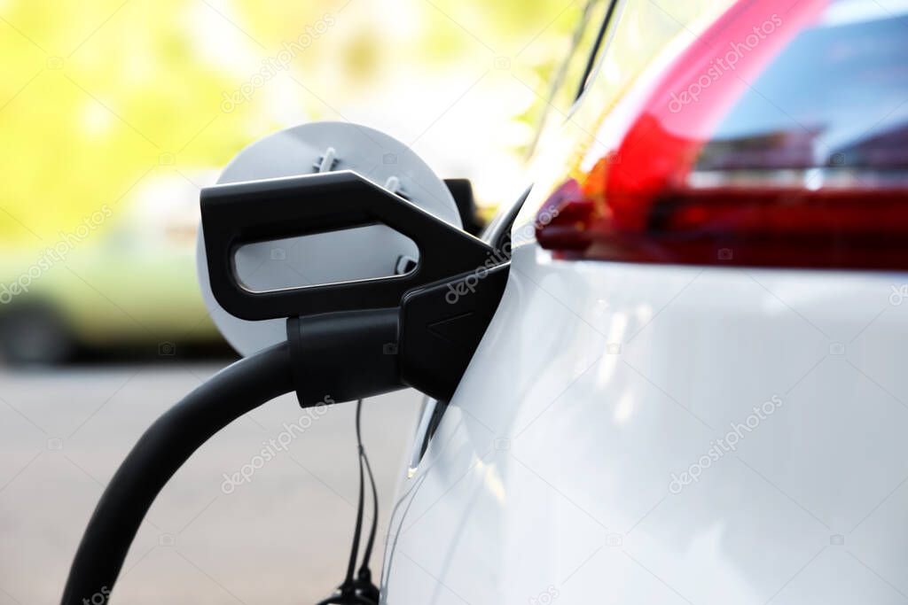 Charging modern electric car from station outdoors, closeup