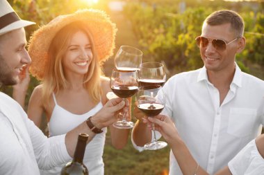 Arkadaşlar, güneşli bir günde üzüm bağında kadeh tokuşturuyorlar.