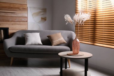 Oturma odasındaki masanın üzerinde dekoratif kurumuş bitkiler olan vazo. İç tasarım