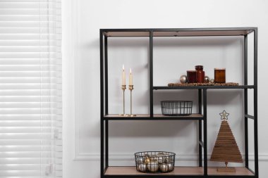 Beyaz duvarın yanında Noel dekoru olan şık bir raf ünitesi. İç tasarım