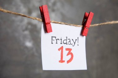 Cuma günü yazılı kağıt! Gri arka planda sicimde 13 asılı duruyor. Kötü şans batıl inanç.