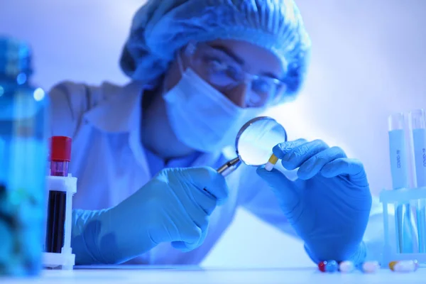 Cientista Com Lupa Examinando Pílula Mesa Laboratório Close — Fotografia de Stock