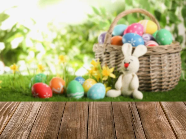 背景上有色彩艳丽的复活节彩蛋的空木制表面和柳条筐 — 图库照片