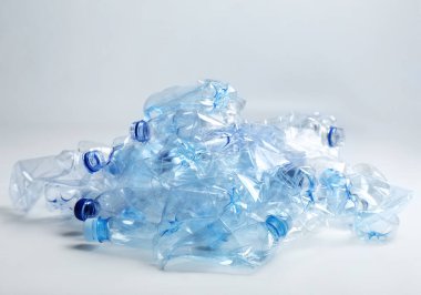 Beyaz arka planda bir yığın kullanılmış plastik şişe. Geri dönüşüm sorunu