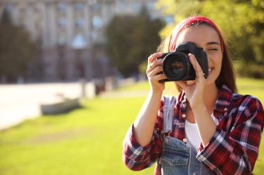 Genç fotoğrafçı dışarıda profesyonel kamerayla fotoğraf çekiyor. Metin için boşluk