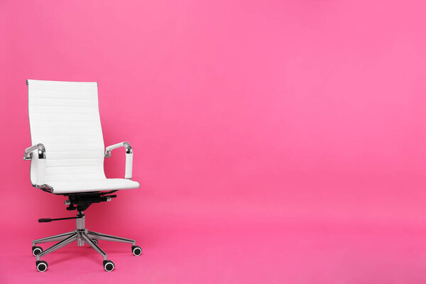 Comfortable office chair on pink background, space for text