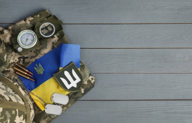 Taktik teçhizat, askeri üniforma ve gri ahşap masada Ukrayna bayrağı. Metin için boşluk