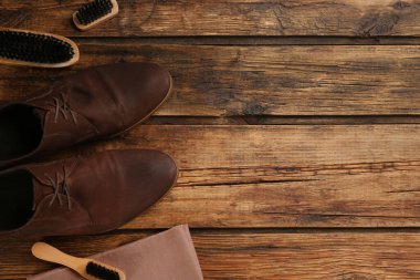 Ahşap masa üzerinde ayakkabı bakım aksesuarları olan şık ayakkabılar. Metin için boşluk