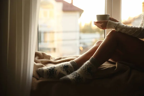 女人们穿着针织袜子 在靠窗的格子布上拿着一杯热饮 特写镜头 — 图库照片