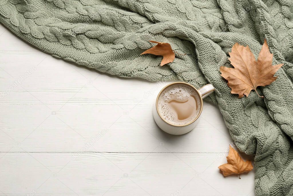 Flat lay composition with coffee and warm plaid on white wooden table, space for text