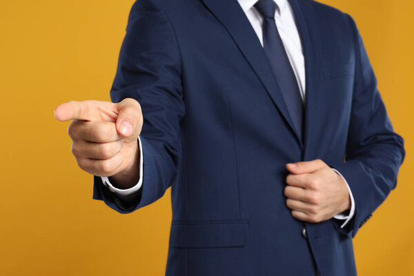 Businessman touching something on yellow background, closeup. Finger gesture