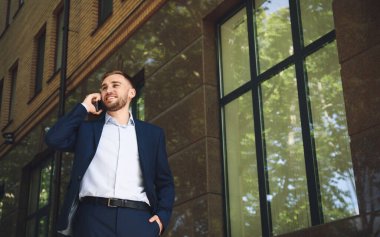 Şehir caddesinde akıllı telefondan konuşan genç adam.