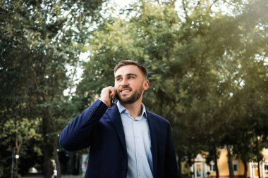 Genç adam parkta akıllı telefondan konuşuyor.
